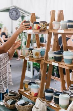 a woman standing next to a wooden stand filled with bowls