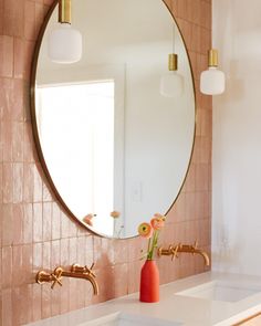 a bathroom sink with a mirror above it and flowers in a vase on the counter