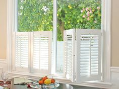 two white shuttered windows with fruit on the table