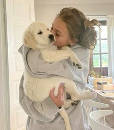 a woman holding a white dog in her arms