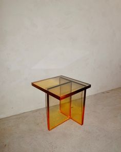 a glass table sitting on top of a cement floor next to a white wall in an empty room