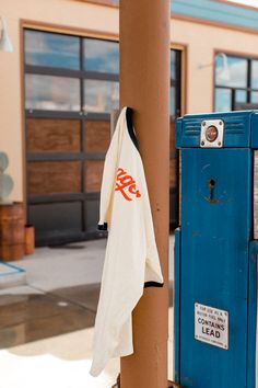 an orange and white towel is hanging on a blue post outside the building with its door open