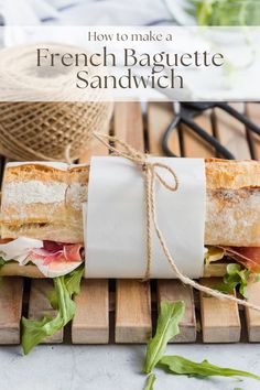 french baguette sandwich wrapped in paper and tied with twine on wooden board