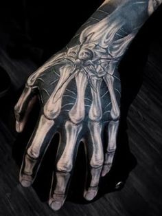 a man's hand with tattoos on it and his hands in the shape of bones