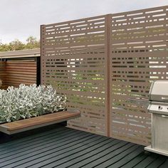 an outdoor kitchen with grill and plants on the decking area, surrounded by wood slats