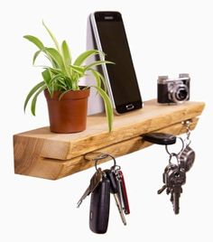 a cell phone is sitting on a wooden shelf with keys and a potted plant