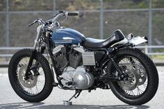 a blue motorcycle parked on the side of a road next to a chain link fence