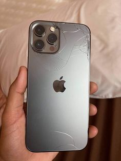 someone holding an iphone in their hand with cracked glass on the front and back side