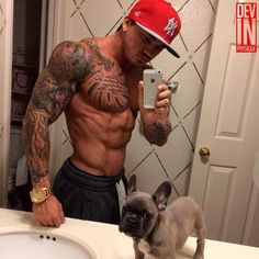 a shirtless man taking a selfie with his dog in front of the bathroom sink