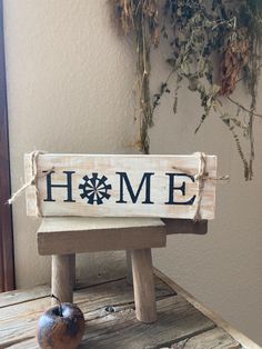 a wooden sign that says home sitting on top of a table next to an apple