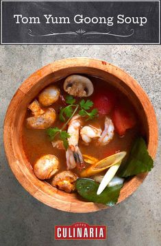 tom yum goong soup in a wooden bowl with shrimp, mushrooms and cilantro