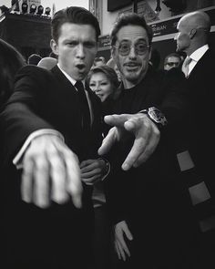 black and white photograph of two men pointing at something in front of them while others look on