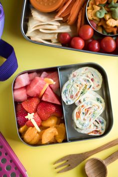 two tins filled with food sitting on top of a yellow table next to utensils