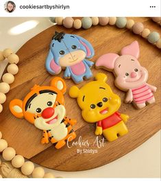 winnie the pooh and friends cookie toppers on a wooden board with beads around it