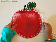 a child's hands holding a red apple with white dots on it