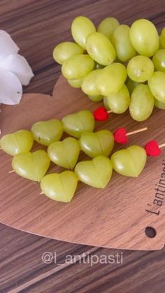 grapes are arranged on a cutting board with toothpicks in the shape of hearts