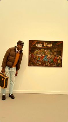 a man is standing in front of a painting and holding a suitcase while looking at the camera