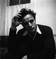 black and white photograph of a young man sitting in front of a window with his hand on his head