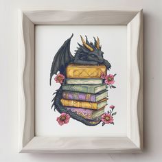 a dragon sitting on top of a pile of books in a white frame with pink flowers