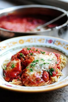 a plate of pasta with sauce and parmesan cheese on the side, sitting on a table