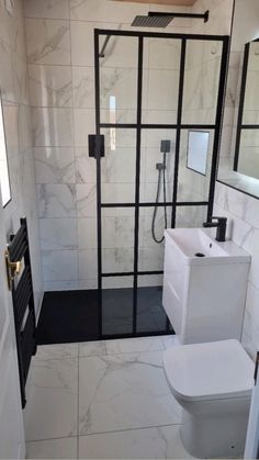 a bathroom with a toilet, sink and shower stall in white marbled tiles on the walls