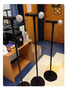 two black poles with silver balls on them in front of a desk and bookshelf