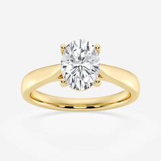 a yellow gold engagement ring with a round cut diamond in the center, on a white background