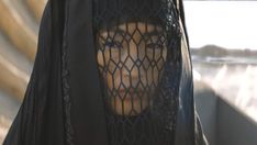 a woman wearing a black veil with her face through the mesh covering it's head