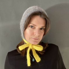 a woman wearing a knitted hat with a yellow scarf around her neck and a blue bead necklace