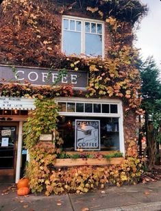 an old building covered in vines and ivy with a coffee shop sign on the front