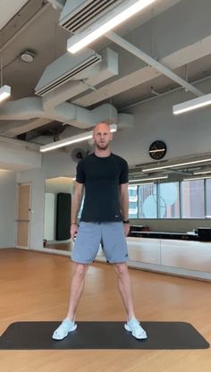 a man standing on top of a yoga mat in an empty room with no one around