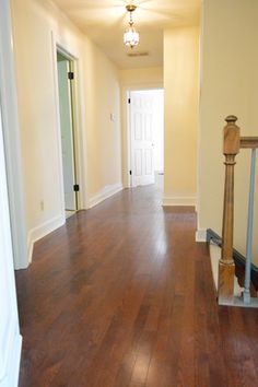 an empty hallway with hard wood floors and white walls