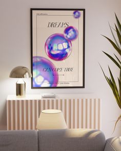 a poster hangs on the wall above a gray couch with a lamp and potted plant