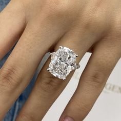 a woman's hand with a diamond ring on top of her finger and an engagement band