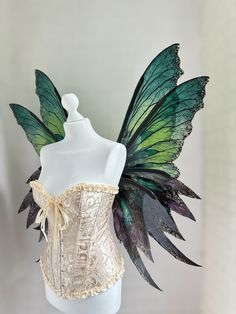 a white mannequin with green and gold wings