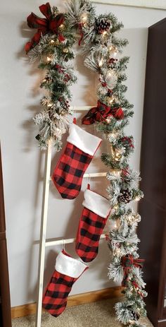 christmas stockings hung on a ladder with pine cones and red and white plaid stocking