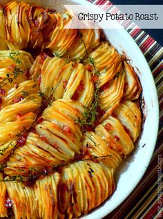 a white bowl filled with cooked potatoes covered in sauce and garnished with herbs