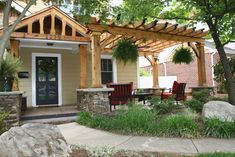 an outdoor patio with chairs and tables under a pergolated arbor in front of a house