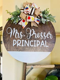 a wooden sign that says mrs preser principals hanging on the wall next to a potted plant