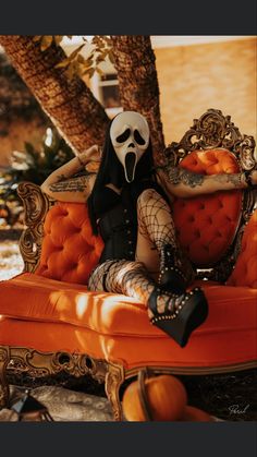 a woman sitting on top of an orange couch with a skeleton face painted on it