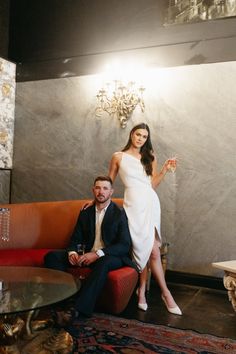 a woman in a white dress sitting on a couch next to a man