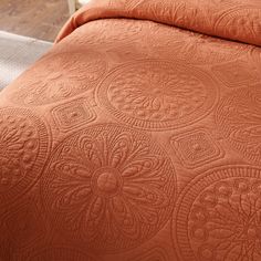 an orange quilted bedspread on a bed