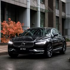 a black volvo car parked on the side of a road in front of a building