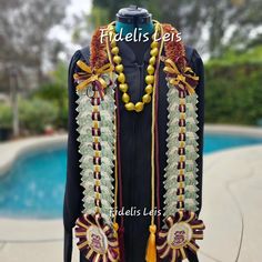 an elaborately decorated dress with beads and tassels stands in front of a pool