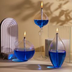 two vases with blue liquid in them on a table next to a radiator