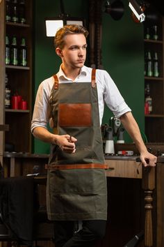 a man in an apron is standing at the bar with his hands on his hips