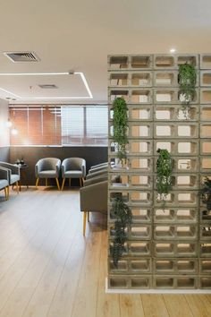 an office with chairs and plants on the wall in front of it's glass doors