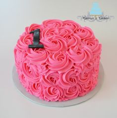 a cake with pink frosting and a black number one on it's top