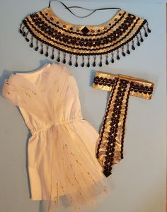 a white dress with black beaded trim and matching accessories on a light blue background