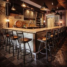 a bar with lots of stools next to it and lights hanging from the ceiling